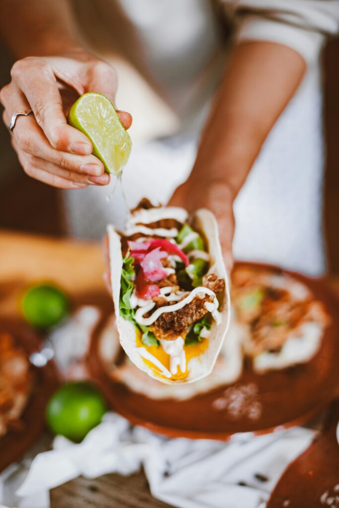 A close-up of a taco with lime juice squeezed over, showcasing vibrant and fresh ingredients.